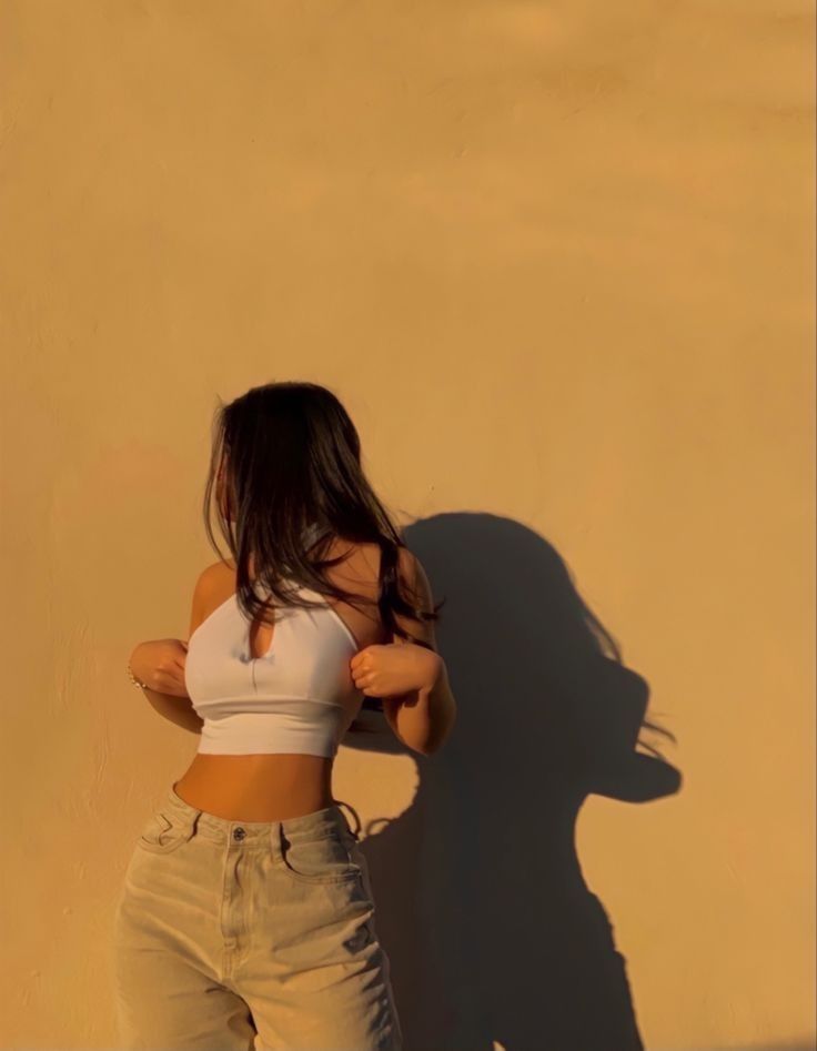 a woman standing in front of a wall with her shadow on the wall behind her