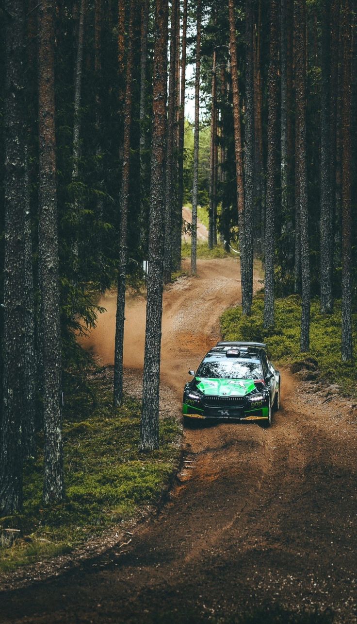 a car driving down a dirt road in the woods