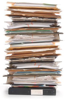 a large stack of papers sitting on top of a black desk next to a white wall