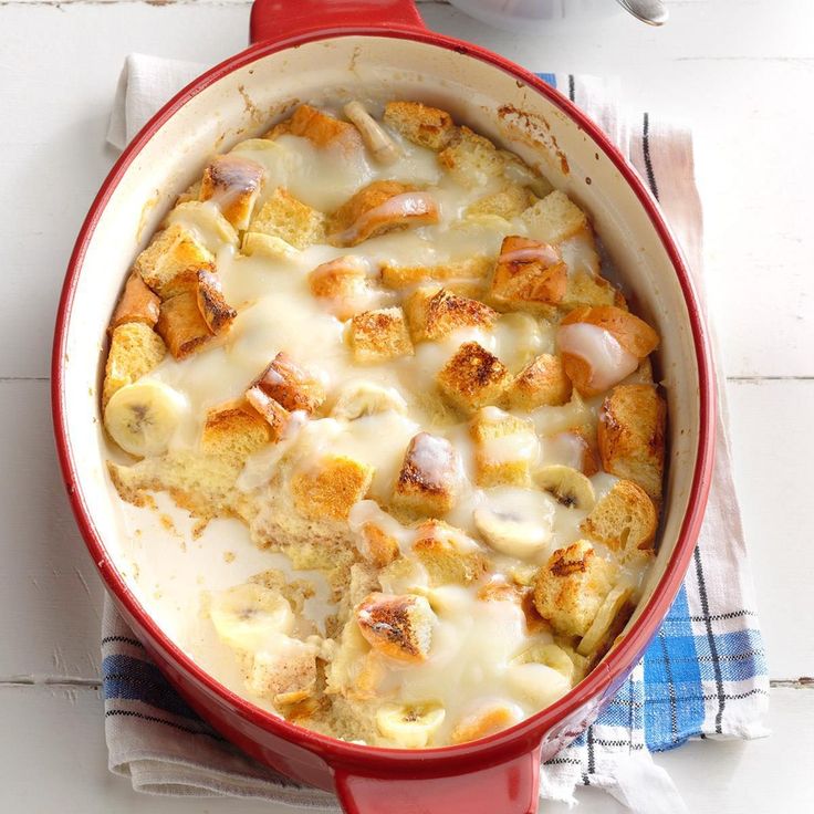 a red casserole dish with cheese and meat in it on a white table