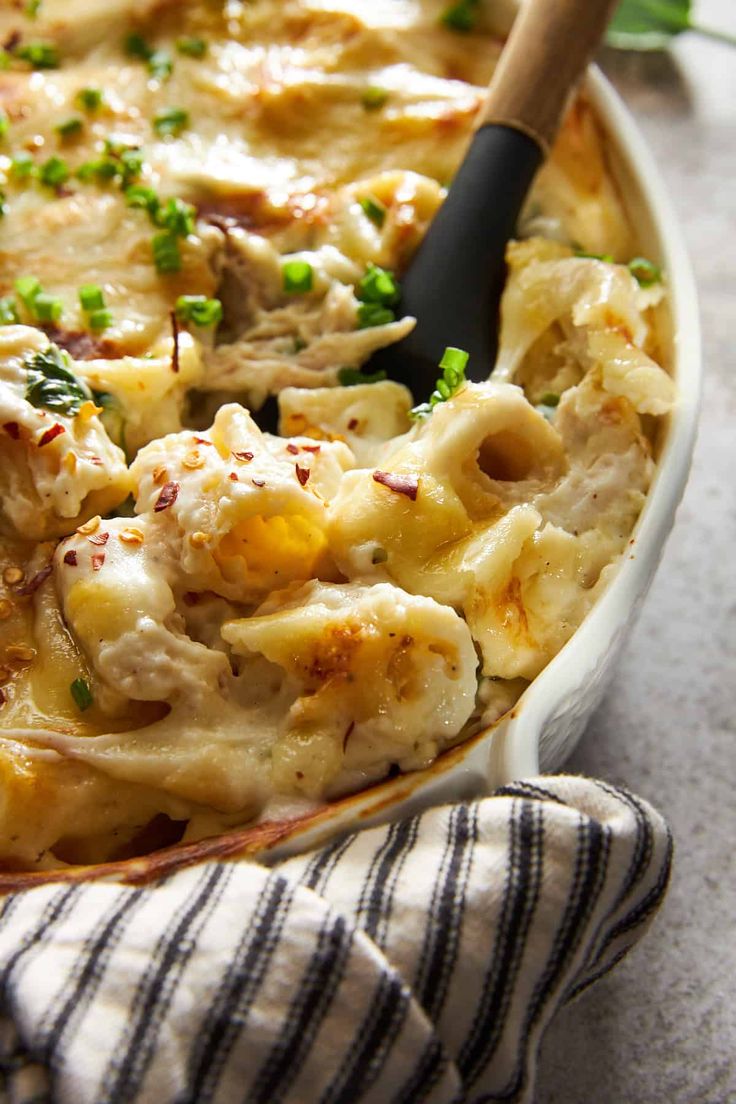 a casserole dish filled with chicken and noodles, garnished with parsley