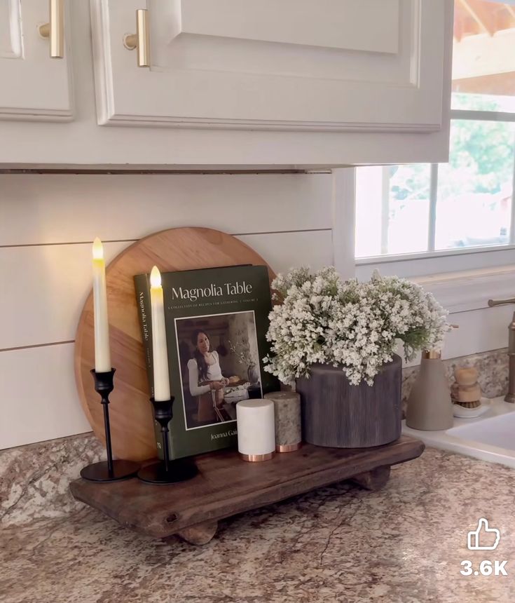 a kitchen counter with candles and flowers on it