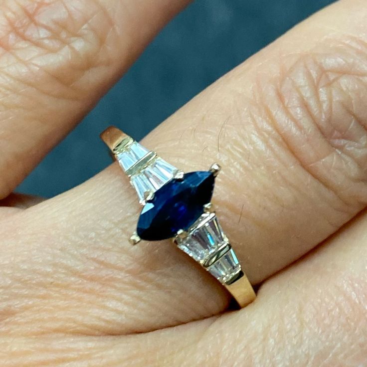 a woman's hand with a ring on it and a blue stone in the middle