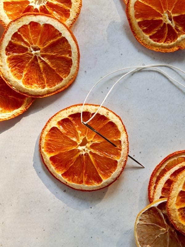 orange slices cut in half on a table with needles and string attached to them, surrounded by strings