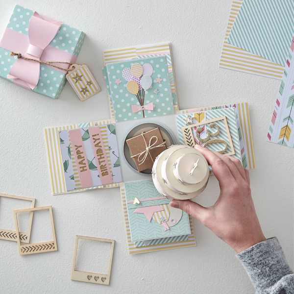 a person's hand holding a cup over some cards and other items on the table