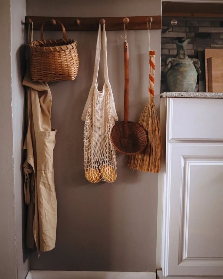 some baskets hanging on the wall with brooms and other items in them next to a door