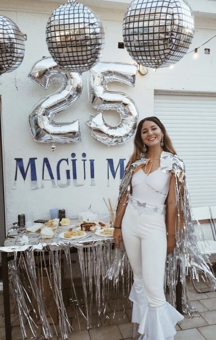 a woman standing in front of a table with silver balloons