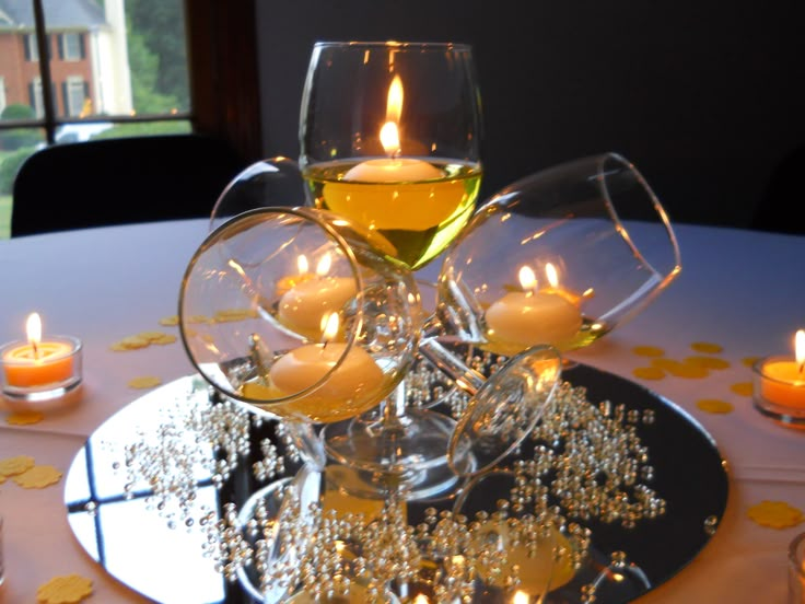 two wine glasses filled with candles on top of a table