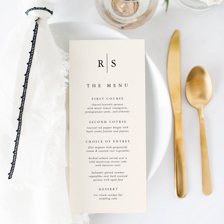 a table setting with gold utensils and menu cards