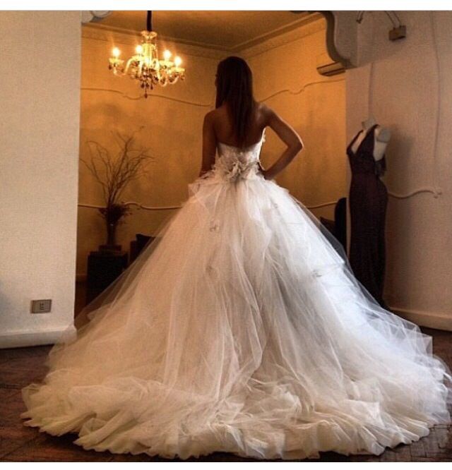 a woman in a white wedding dress standing next to a chandelier