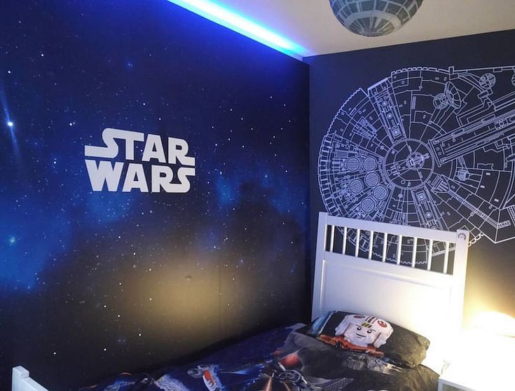 a bedroom with a star wars theme painted on the wall and a bed in front of it