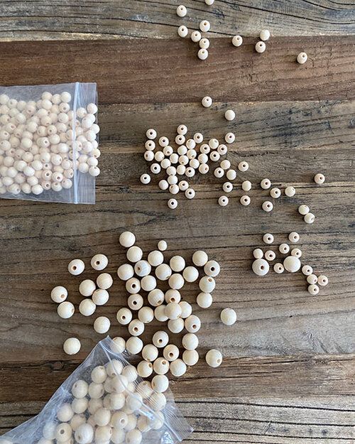 some white beads are laying on a wooden table next to plastic bags with holes in them