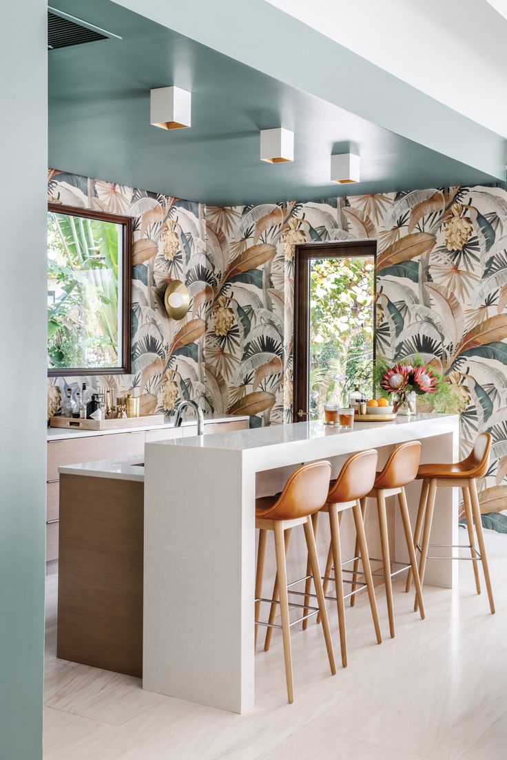 the kitchen is decorated with tropical wallpaper and bar stools