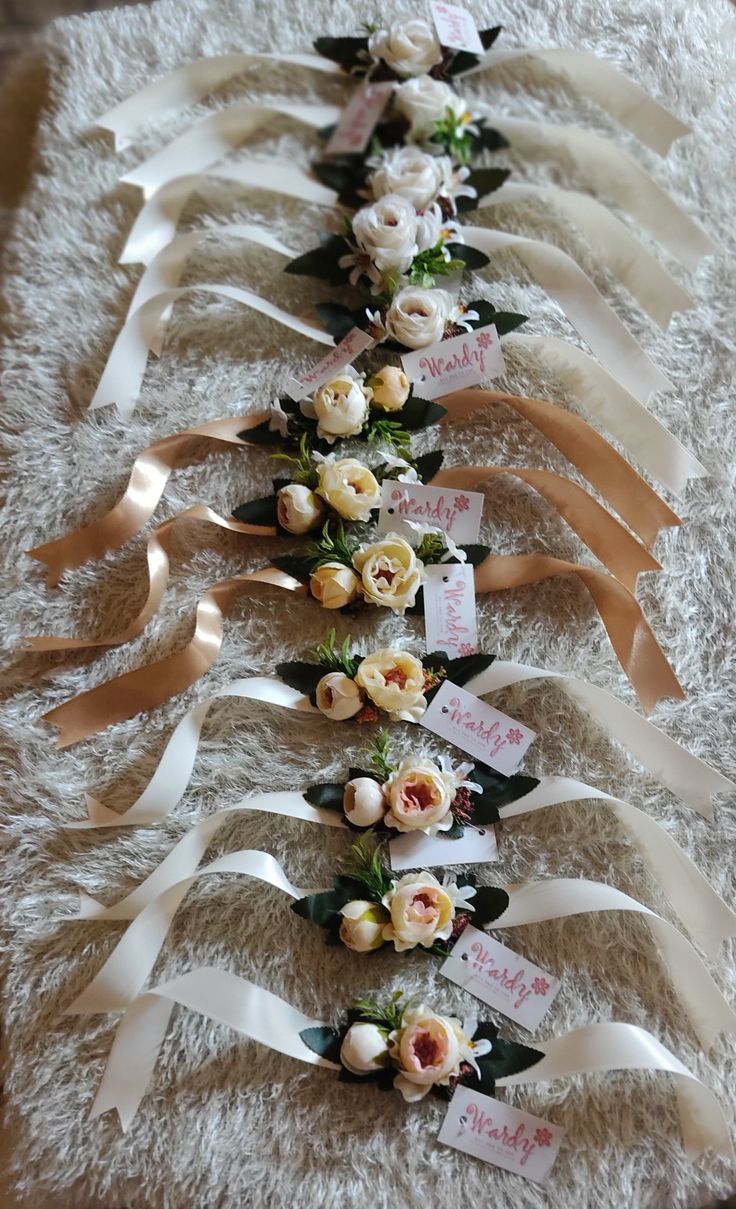 a row of ribbons with flowers and name tags on them are lined up against a white carpet