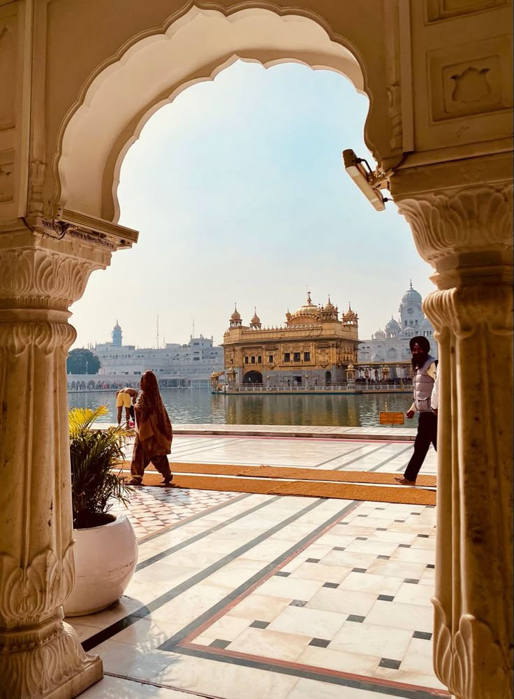 two people walking through an archway in front of the golden temple, amritha