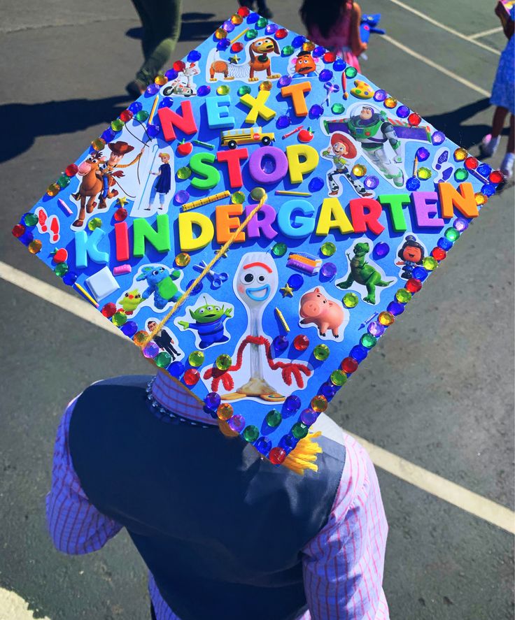 a child's graduation cap decorated with cartoon characters and letters is held up in the air