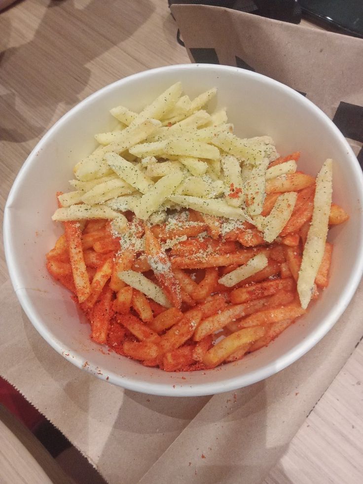 a white bowl filled with pasta and sauce on top of a wooden table next to a brown paper bag