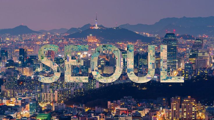 the word seoul in front of a cityscape with mountains and buildings at night