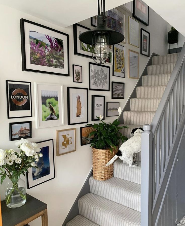 a staircase with pictures on the wall and flowers in a vase next to it,