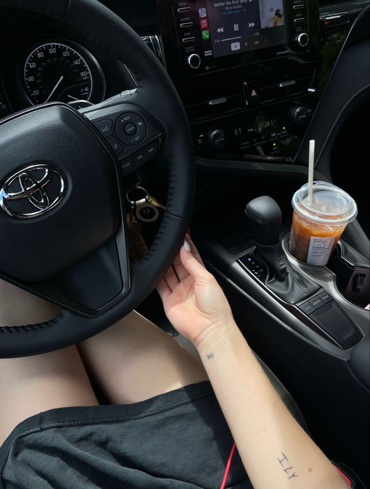 a woman is sitting behind the wheel of a car with her hand on the steering wheel