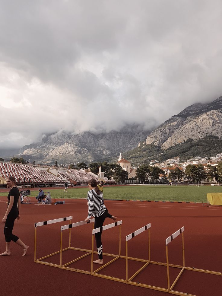 two people walking on a track with mountains in the backgrouds behind them