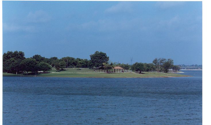 an island in the middle of a body of water with trees and houses on it