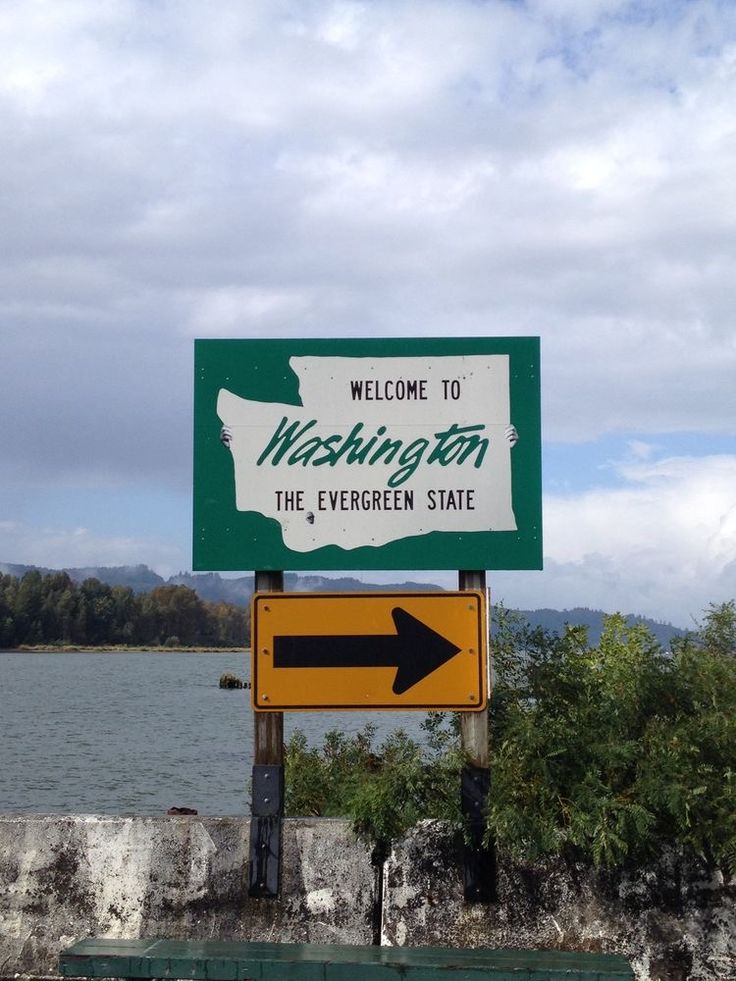 a green and white sign that says welcome to washington the evergreen state with an arrow pointing in opposite directions