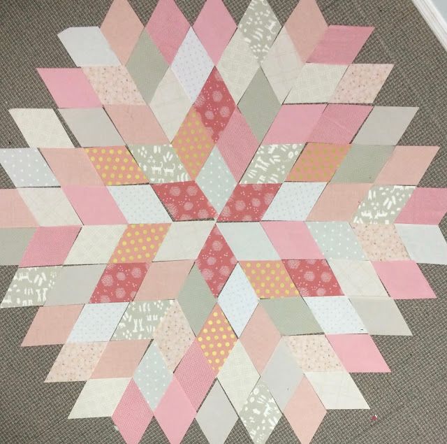 a pink and grey patchwork quilt on the floor