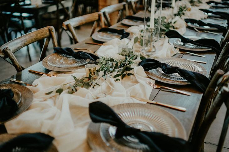 the table is set with plates and black napkins