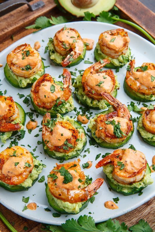 a plate filled with shrimp and cucumbers on top of a wooden table