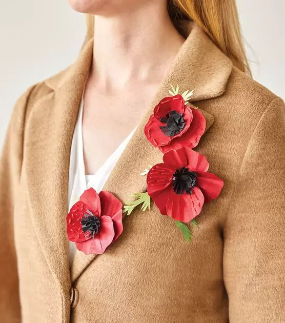 a woman with red flowers on her jacket and text that reads craft paper poppy brooches for memorial day