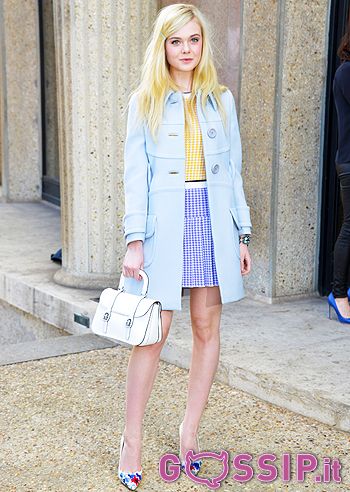 a woman in a blue coat and dress holding a white purse