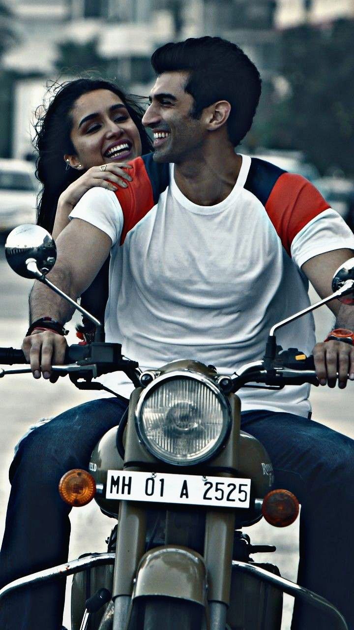 a man and woman riding on the back of a motorcycle