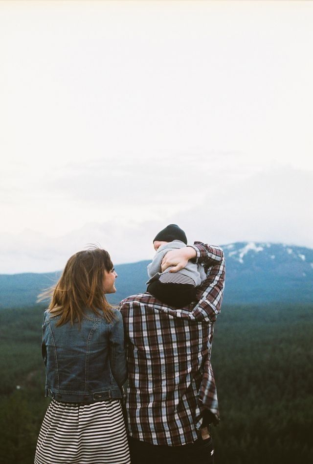 two people standing next to each other on top of a hill