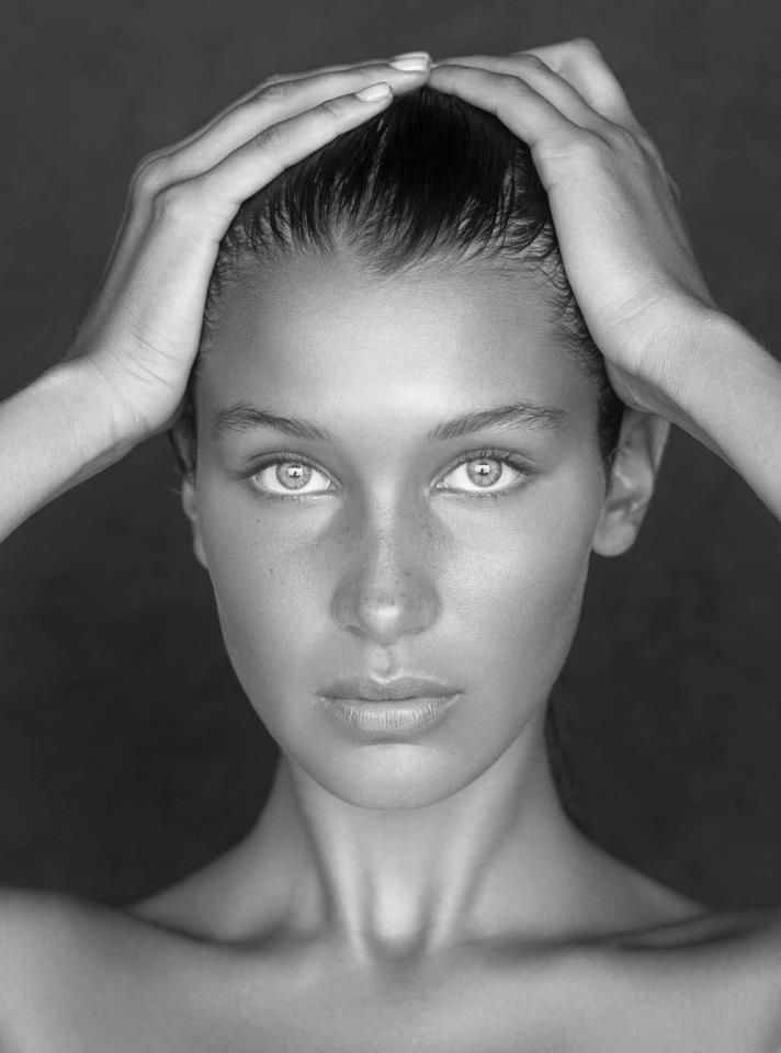 a black and white photo of a woman's face with hands on her head