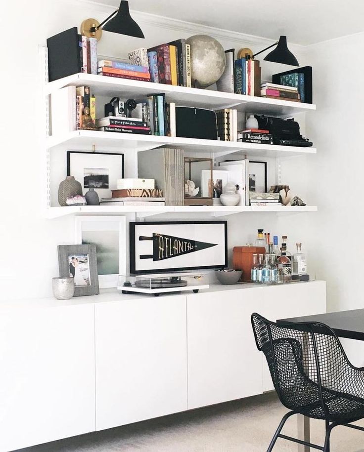 a black and white dining room with bookshelves on the wall next to a table