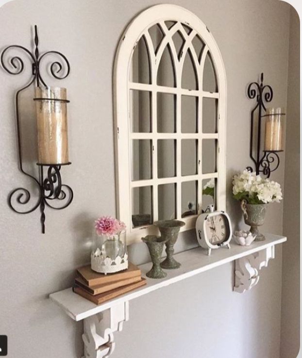 a shelf with candles, vases and flowers on it