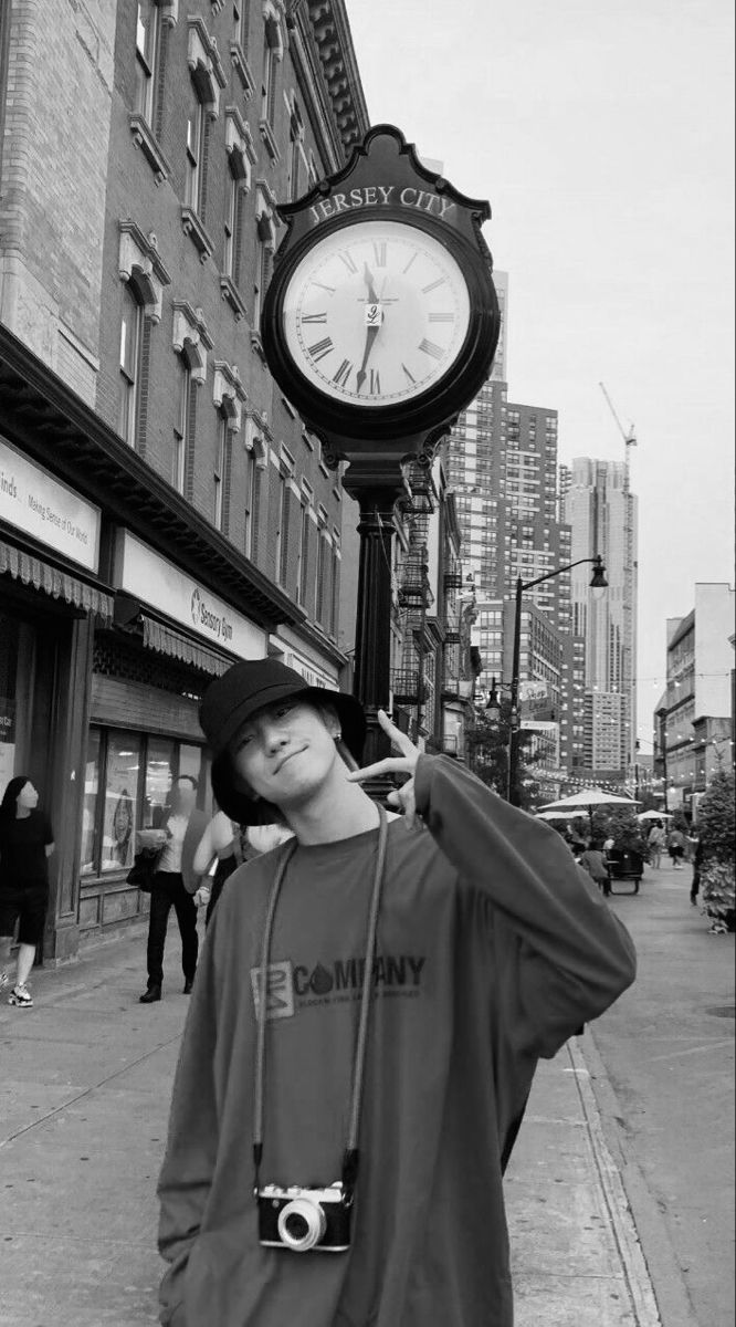 a man standing next to a clock on the side of a road