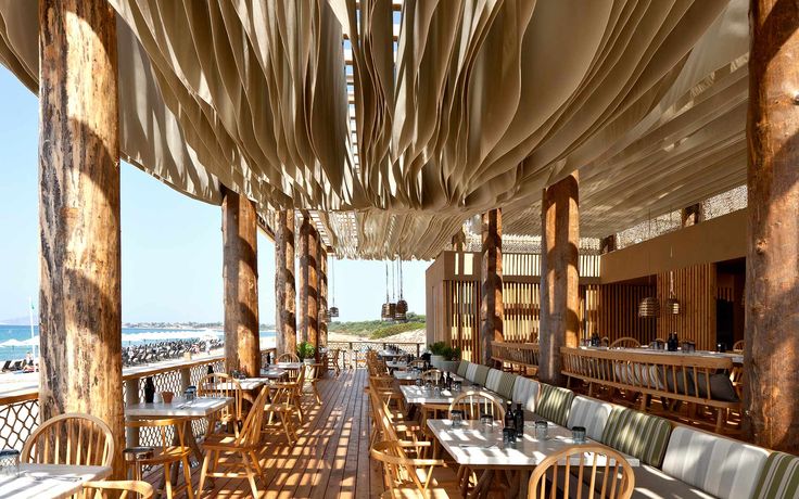 an outdoor dining area with wooden tables and chairs, covered by large sheeted coverings