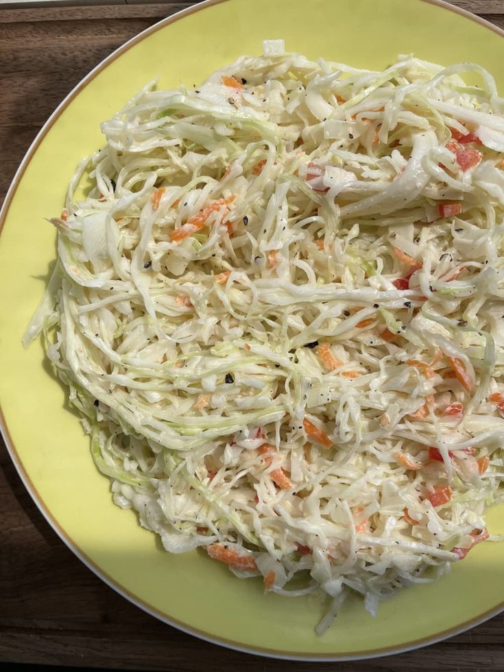 a yellow plate topped with coleslaw and carrots