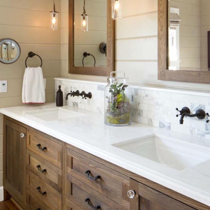 a bathroom with two sinks, mirrors and lights on the wall above them is shown