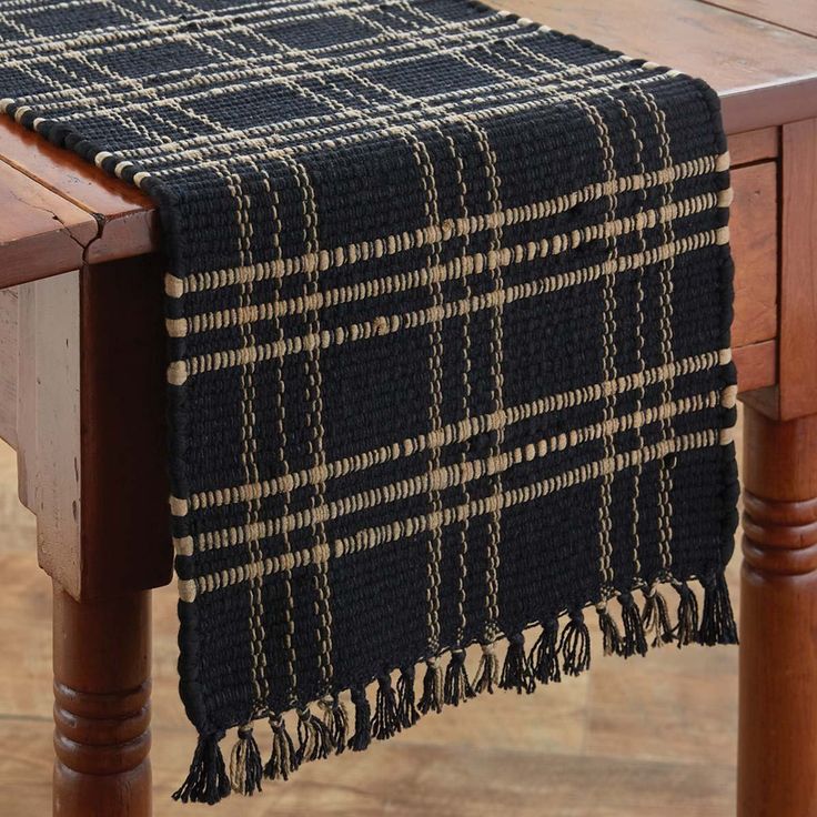 a black and white plaid table runner on top of a wooden table with wood legs