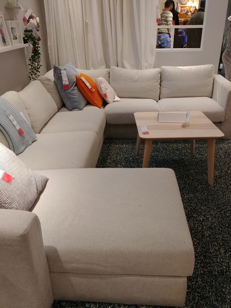 a living room filled with lots of white furniture and pillows on top of couches