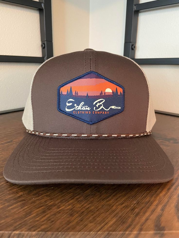 Ethan b. Clothing Co. Sunset hat. Hat color Brown/Khaki Pro-stitched finish CROWN: Mid-Profile, Pro-Model VISOR: Curved CLOSURE: Snapback FABRIC: Cotton Blend, Trucker Mesh Brown Six-panel Trucker Hat For Outdoor Activities, Brown Six-panel Hat For Outdoor Activities, Brown Flat Brim Sports Hat, Brown Flat Bill Sports Hat, Brown Six-panel Outdoor Hats, Sports Flat Bill Hat In Brown, Brown Hiking Cap, Brown Baseball Cap Trucker Hat For Hiking, Brown Trucker Hat With Curved Brim For Sports