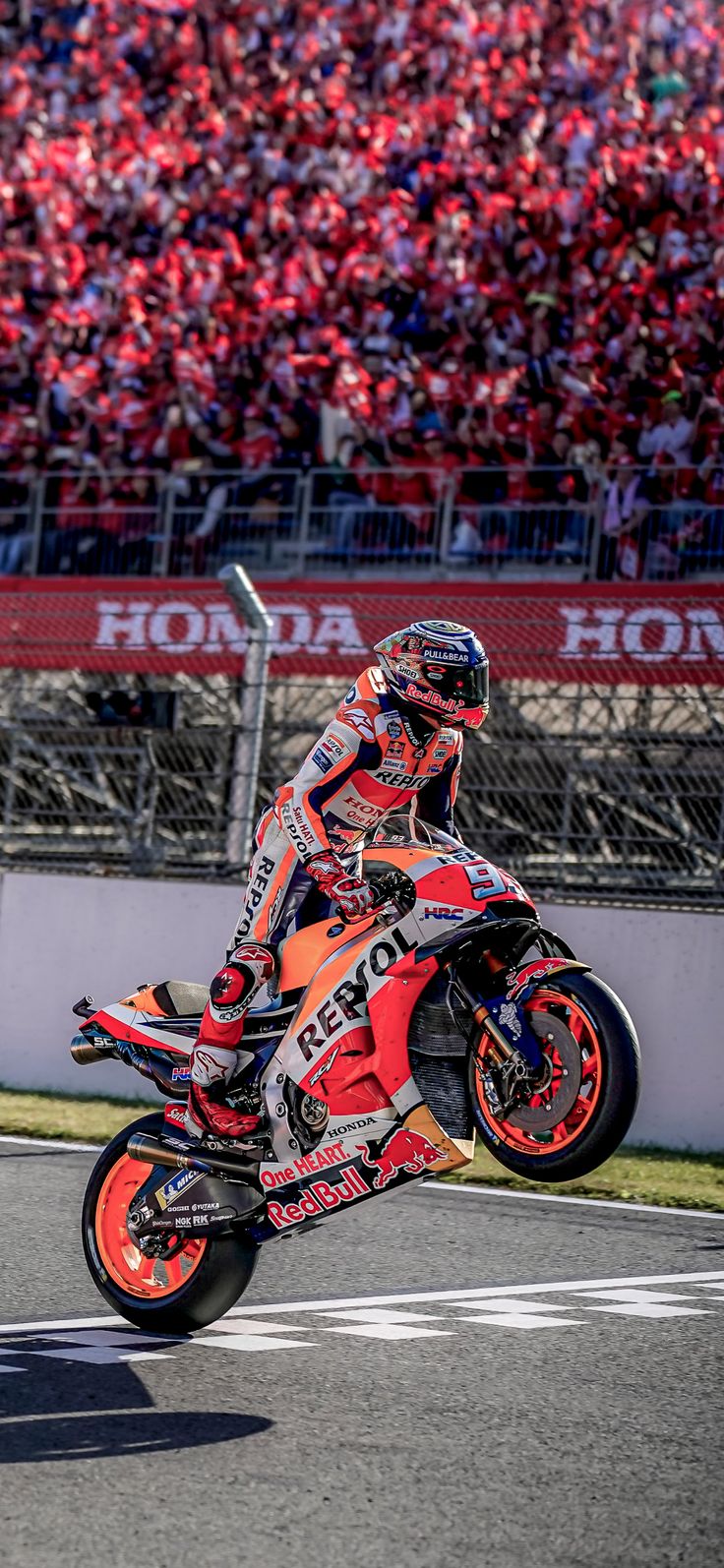 a man riding a motorcycle on top of a race track next to a large crowd