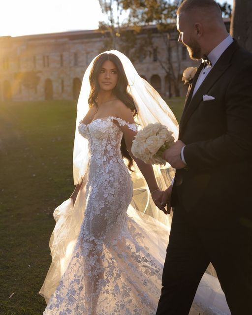 the bride and groom are walking together in their wedding gowns, holding hands with each other