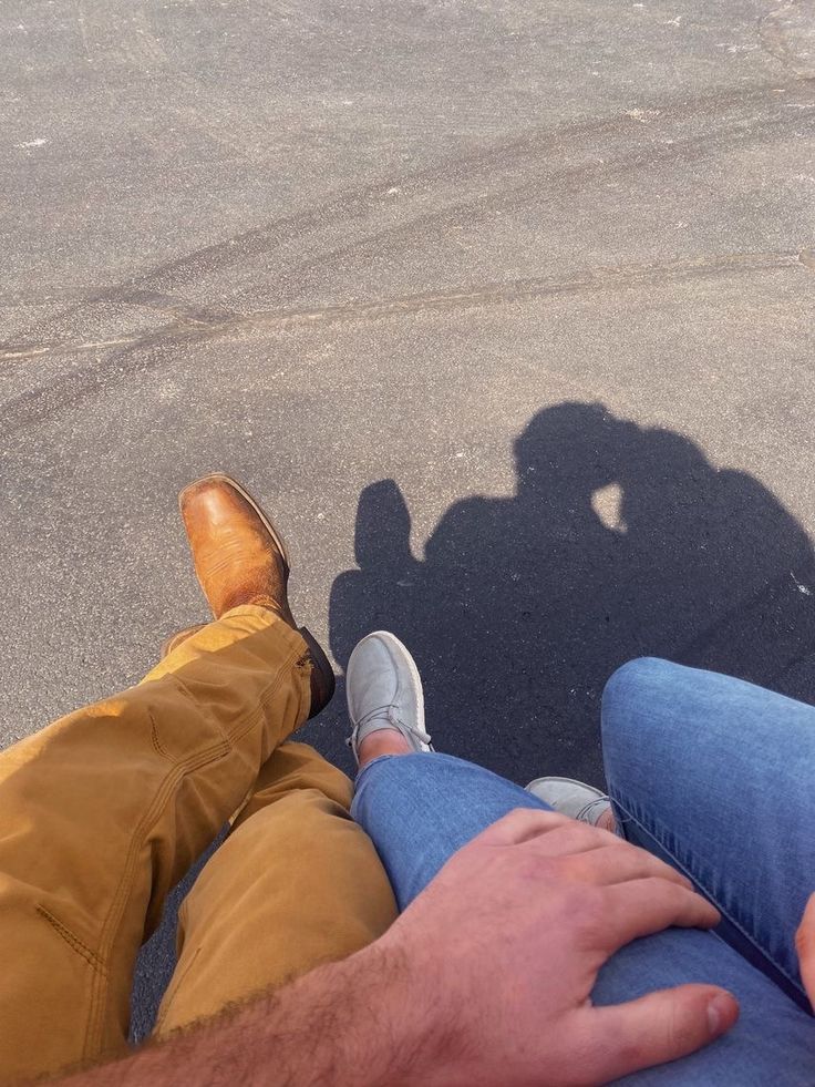 two people are sitting on the ground with their feet up and one person is holding his hand