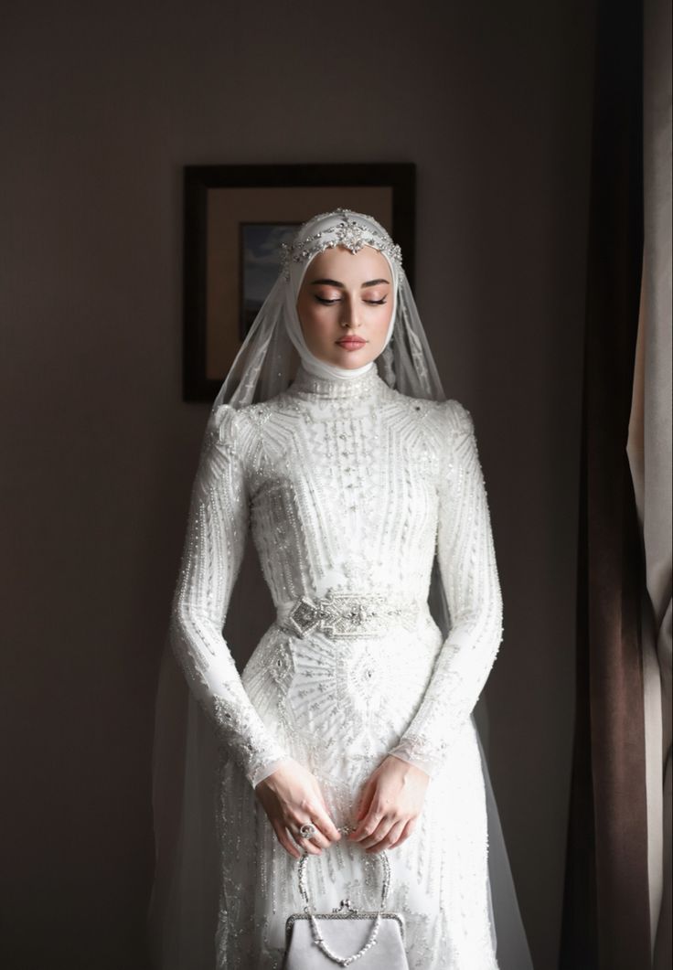 a woman in a white wedding dress and veil holding a purse with her eyes closed