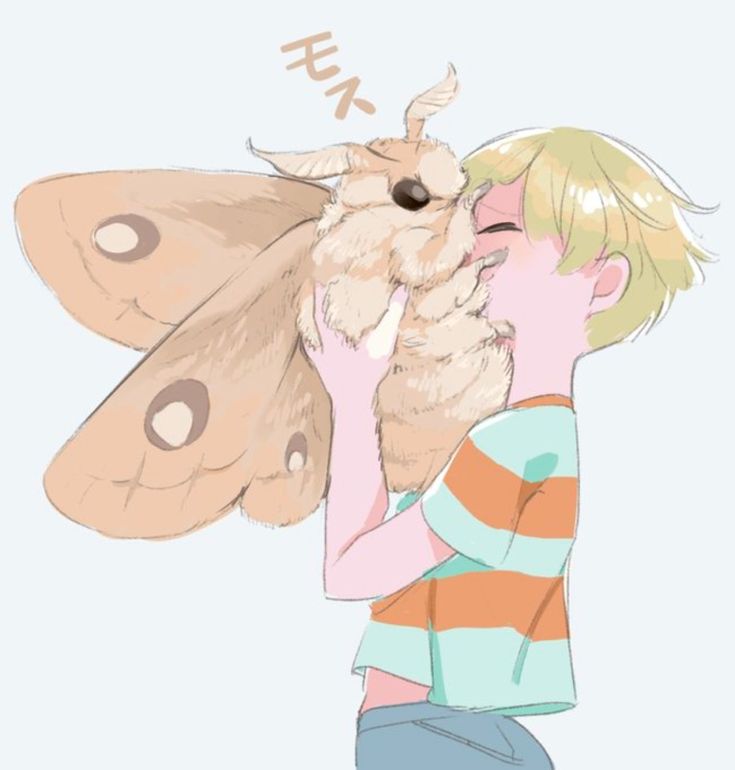 a boy is holding a moth in his hand and looking at it's face