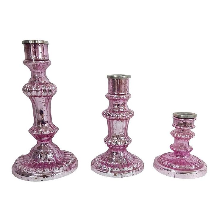 three pink glass candlesticks are shown on a white background and one is empty